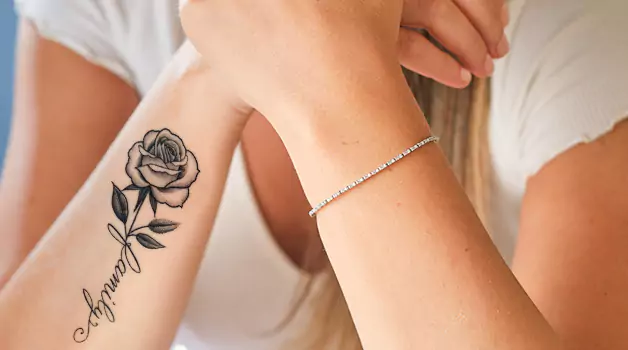 Rose tattoo with a name on various body parts and their meaning
