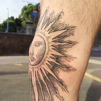 Tribal sun on kneecap tattoo