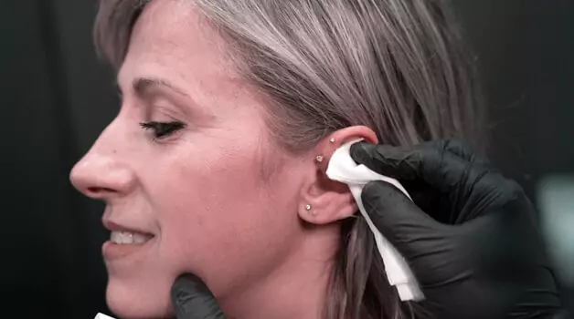 How should I clean my old pierced ears to remove crusts